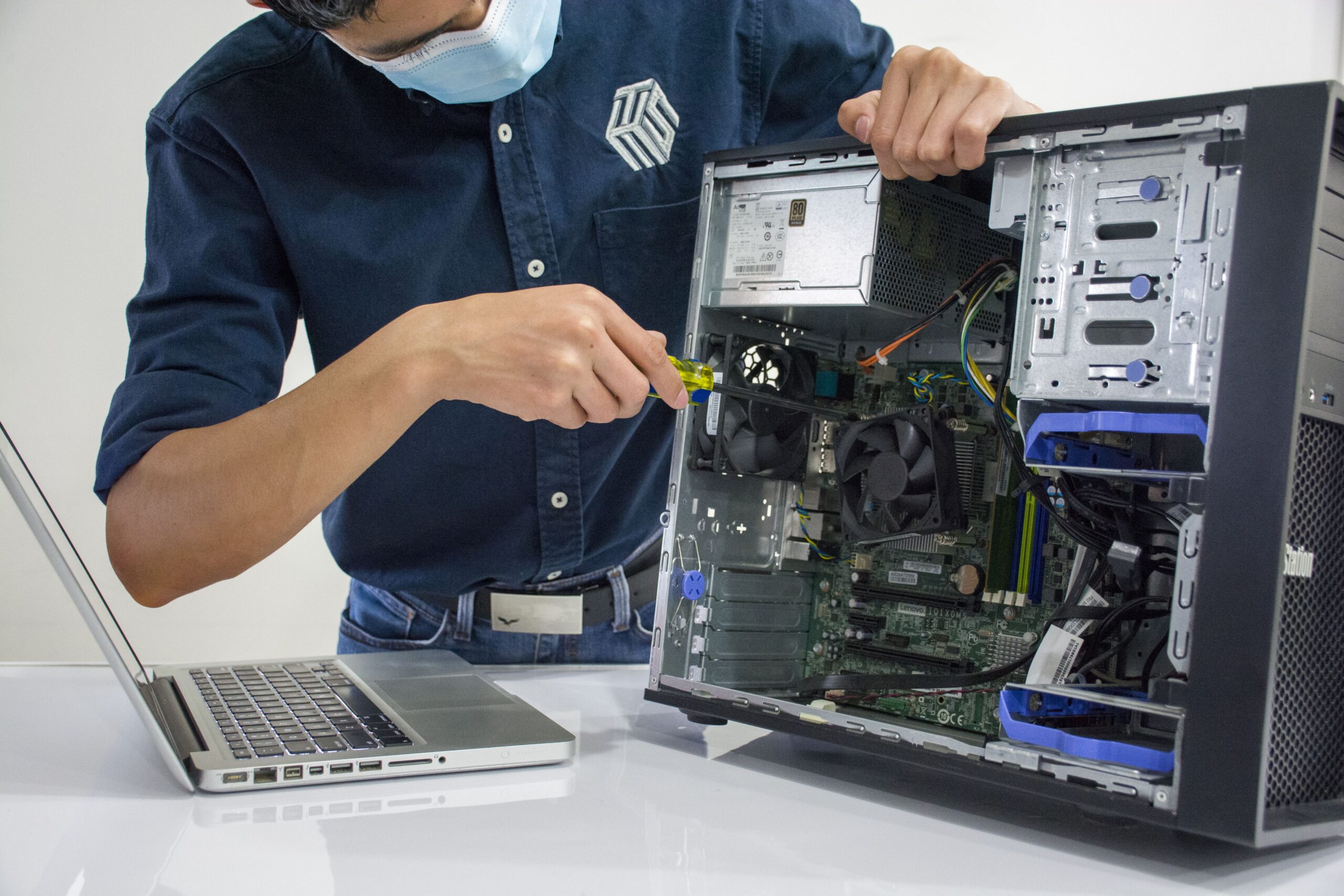 services-01 A technician repairs a desktop computer in an indoor setting, illustrating tech maintenance.