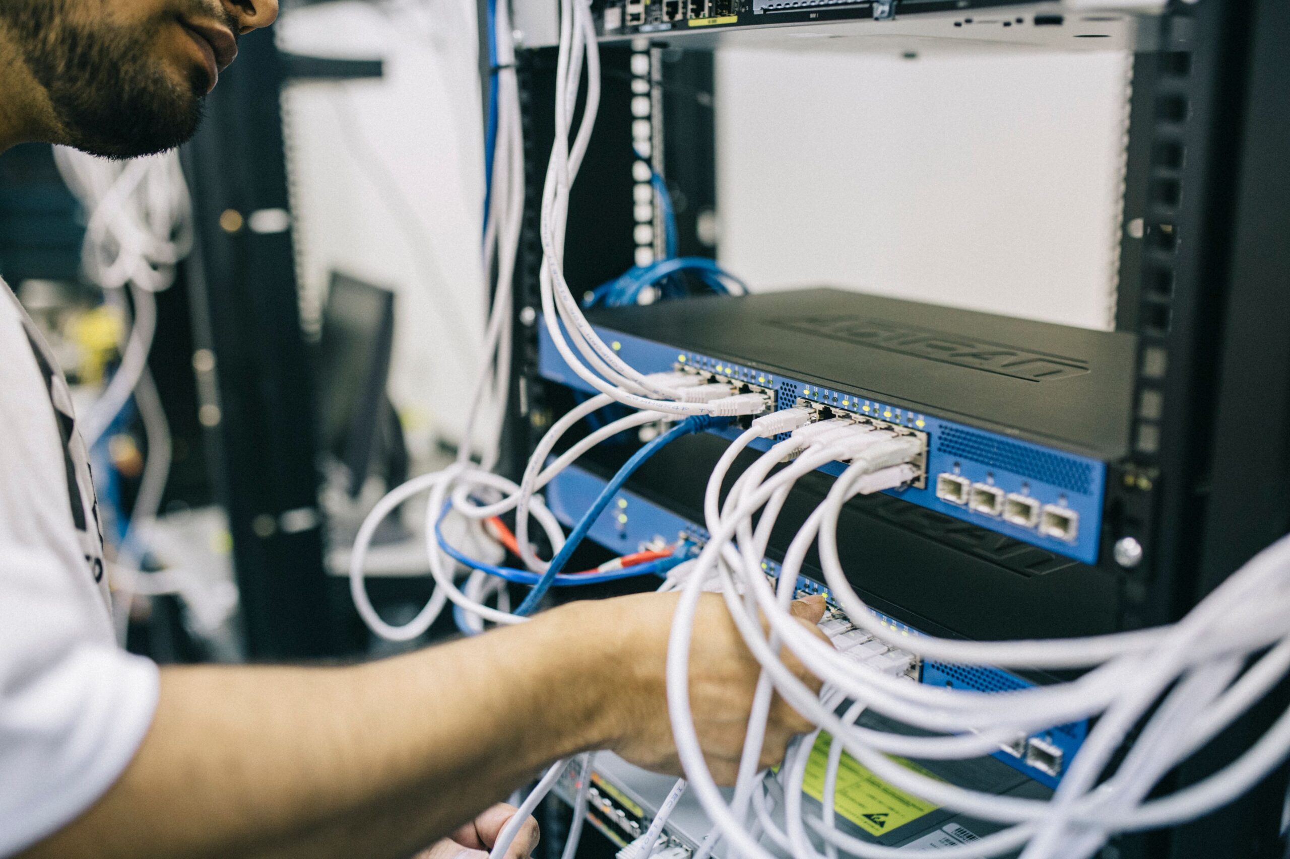 services-01 An IT professional configuring network cables in a server rack, focusing on Ethernet connections.