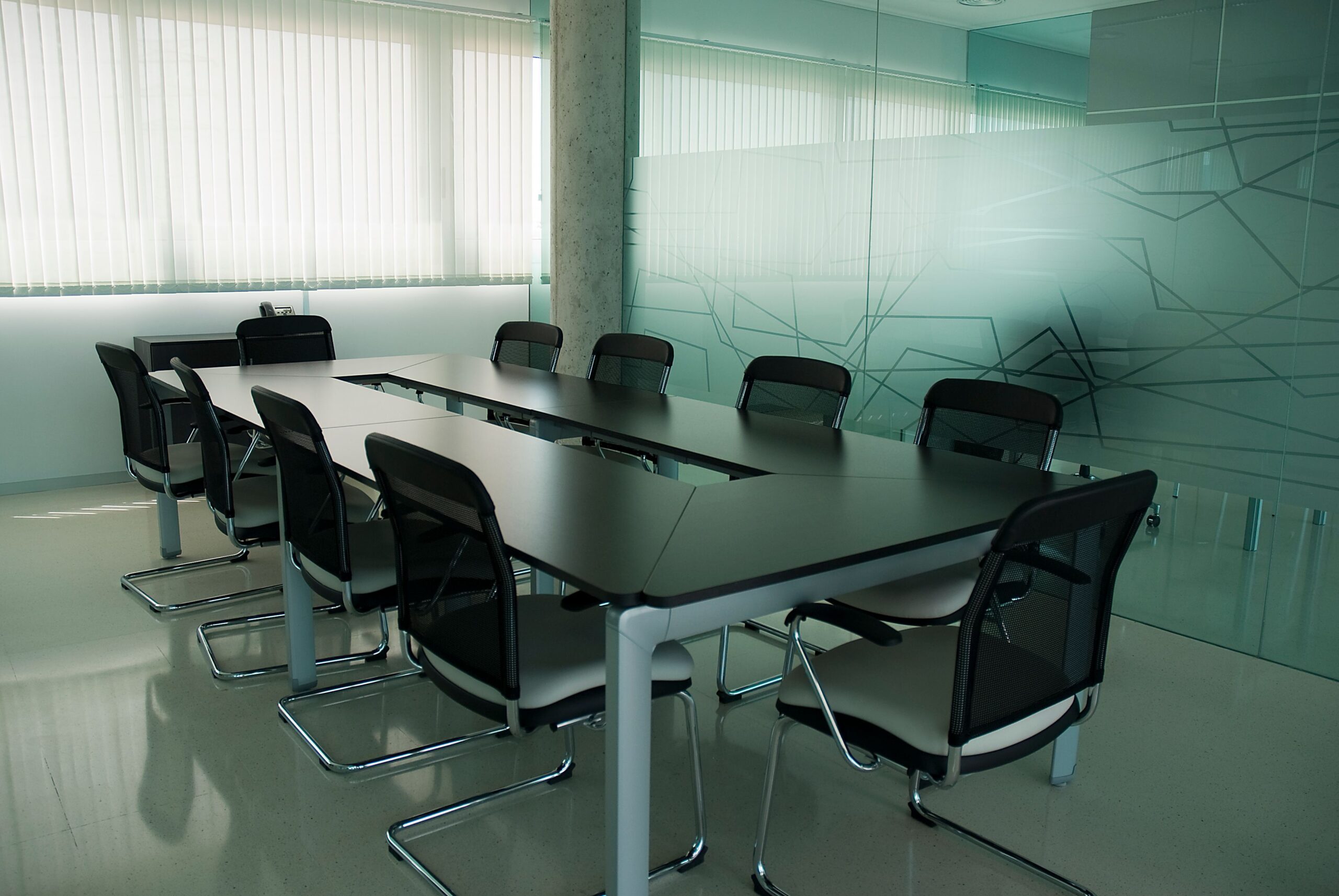 services-01 Elegant conference room with sleek black chairs and a modern glass wall design.