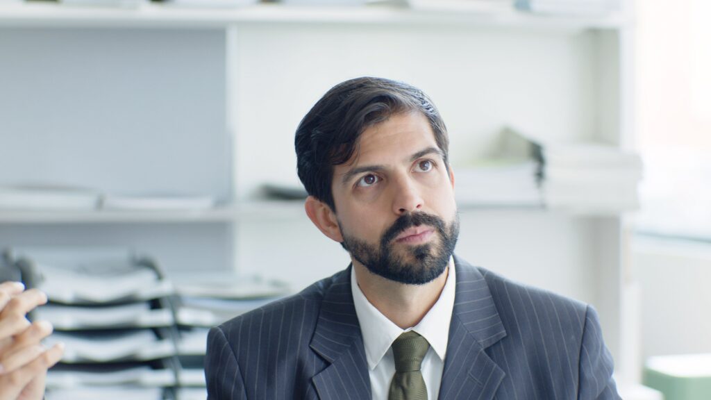 Thoughtful businessman in suit and tie in modern office environment.