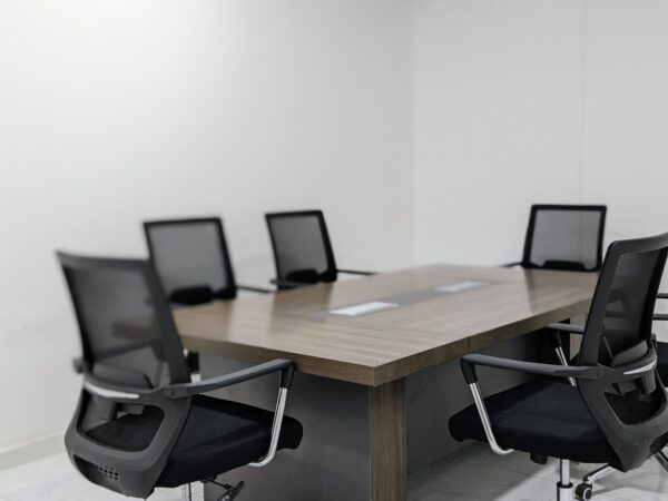 Empty modern office conference room featuring sleek black chairs and a wooden table.